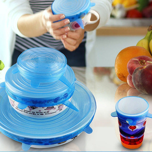 Blue silicone lid on a kitchen counter with colorful cups and fruits in the background