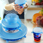 Blue silicone lid on a kitchen counter with colorful cups and fruits in the background