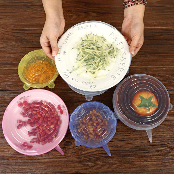Colorful silicone lids on bowls with food on a wooden surface