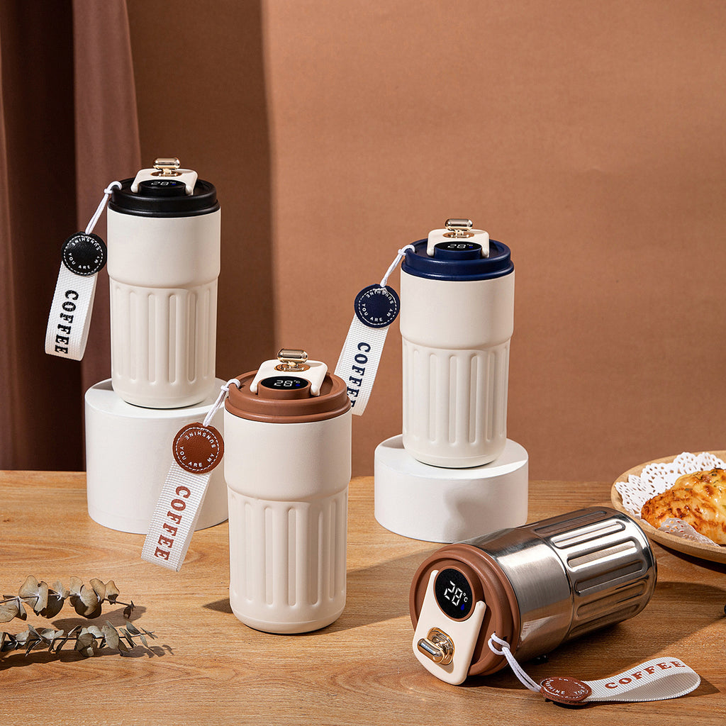Set of white Smart Insulated Coffee Cup with different colored lids on a wooden surface.